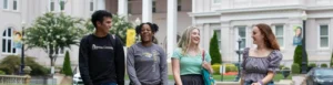 Students smiling and walking on campus, enjoying a bright day in front of university buildings and greenery.